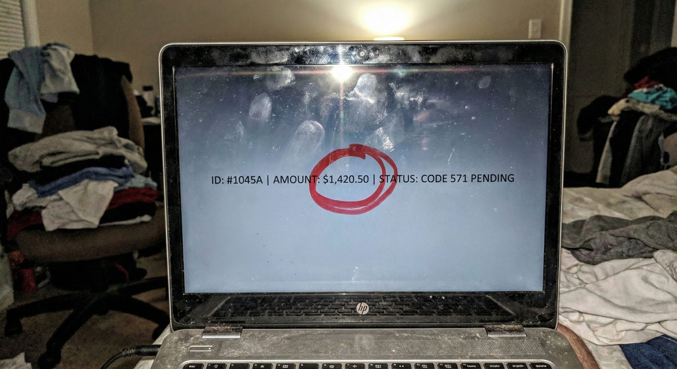 A smudged laptop screen in a dark room displaying an IRS tax transcript with Code 571 and a pending refund amount.