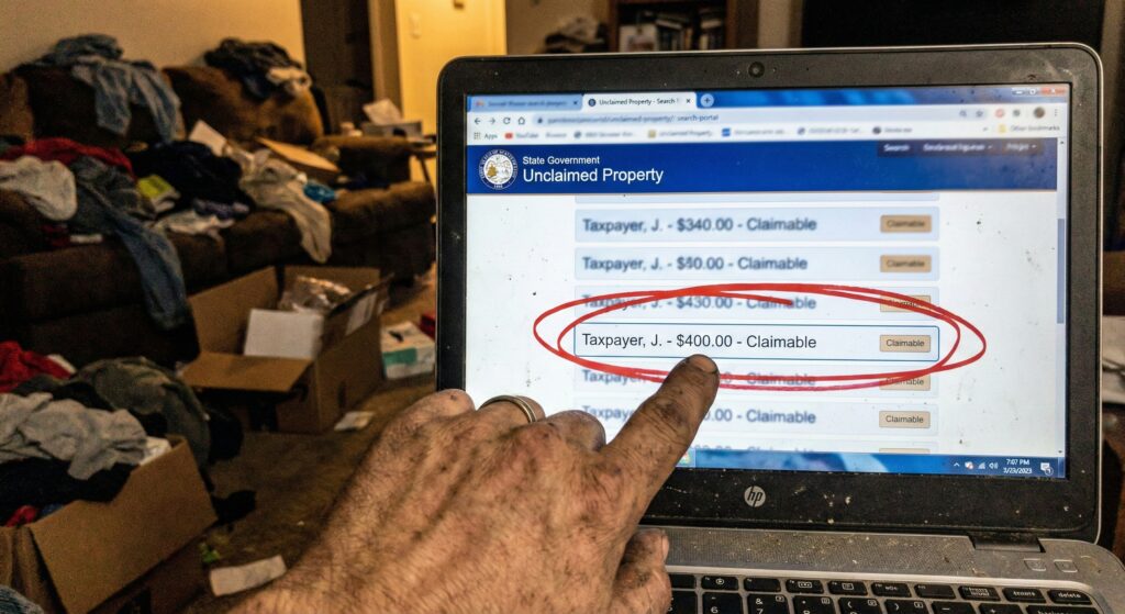 Laptop screen showing "Claim Found" on a state treasury website with the dollar amount circled in red marker.