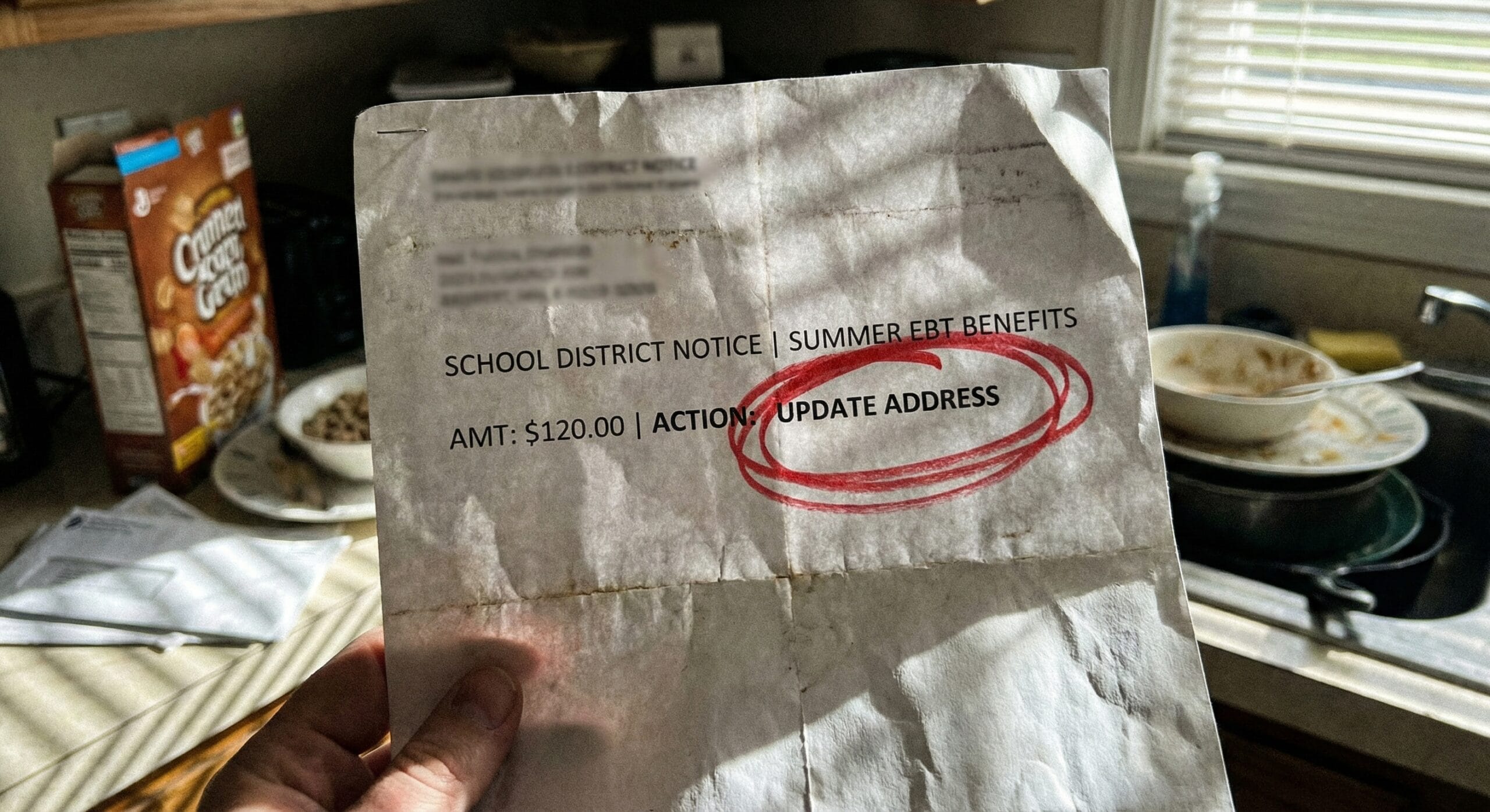 A crumpled official school letter about Summer EBT Sun Bucks on a messy kitchen table.