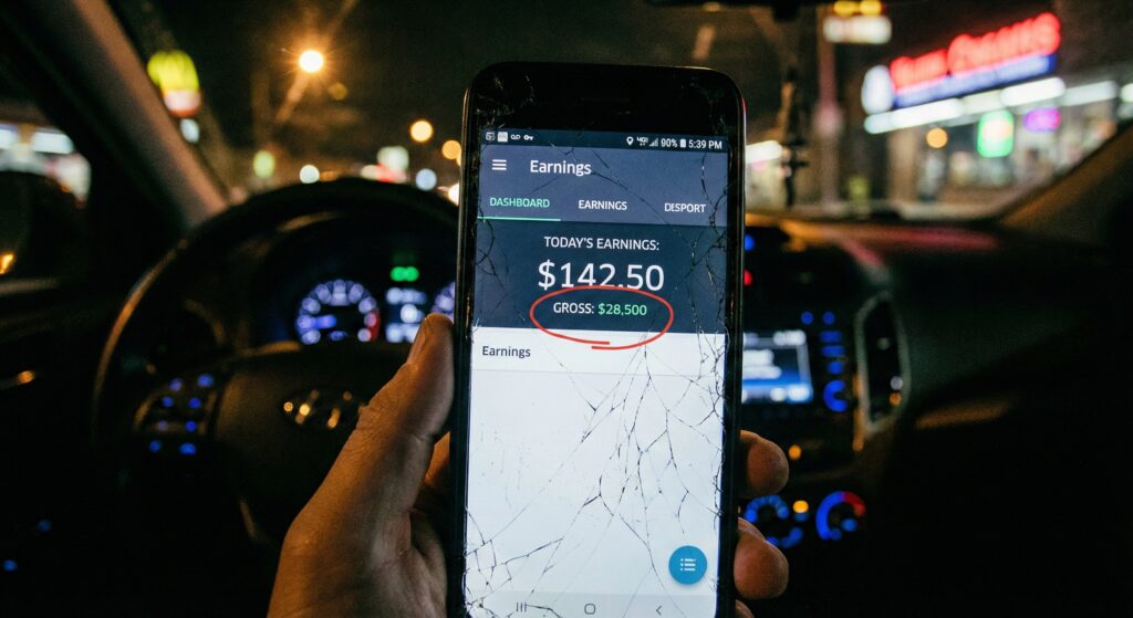 A cracked smartphone screen displaying a gig economy driver dashboard showing daily earnings.